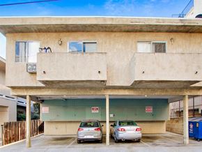 Los Angeles apartment for rent - Two cars are parked in a garage under a concrete building.