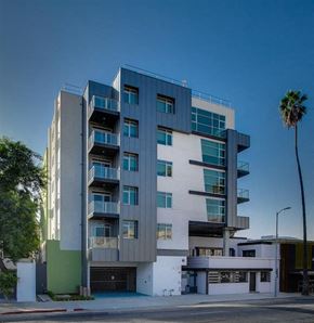 Los Angeles apartment for rent - A modern multi-story building with balconies and a palm tree in front.