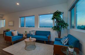 Los Angeles apartment for rent - A living room with a blue sofa and a large window overlooking the city.