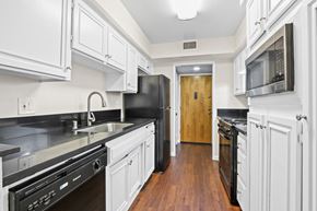 Sherman Oaks apartment for rent - a kitchen with white cabinets and black appliances and a door to a hallway