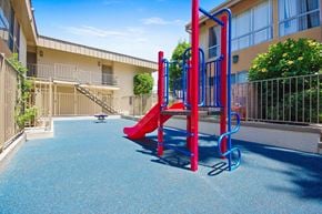 Northridge apartment for rent - A playground with a red slide and blue play equipment.
