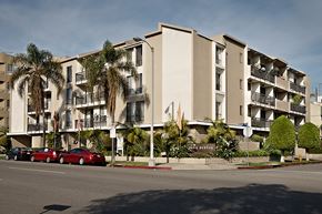 Los Angeles apartment for rent - A row of apartment buildings with cars parked in front.