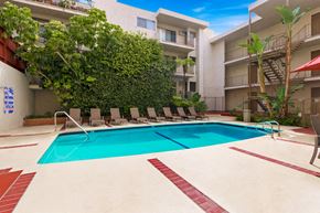 Los Angeles apartment for rent - A swimming pool surrounded by a green wall and lounge chairs.