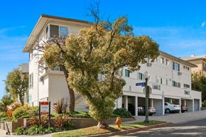 Los Angeles apartment for rent - A tree in front of a white building with a sign in front of it.