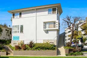Los Angeles apartment for rent - A white two-story building with a blue sign on the front.