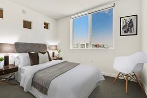 Glendale apartment for rent - A bedroom with a large bed and a white chair.