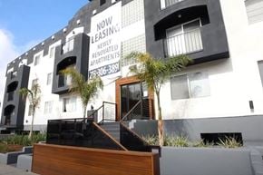 Los Angeles apartment for rent - A modern building with a sign that says "Now Leasing: Newly Renovated Apartments" and a phone number.