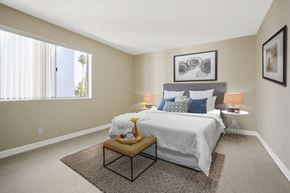 Los Angeles apartment for rent - A bedroom with a large bed and a small table with a vase on it.