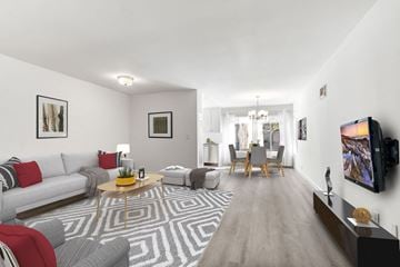 Los Angeles apartment for rent - A living room with a grey and white patterned rug, a grey sofa, a wooden coffee table, and a television on the wall.