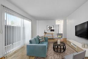 Los Angeles apartment for rent - A living room with a blue couch, a black coffee table, and a flat screen TV mounted on the wall.