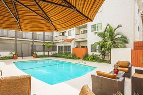 Van Nuys apartment for rent - A pool surrounded by chairs and a brown umbrella.