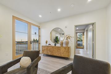 Los Angeles apartment for rent - A living room with a brown couch and a round mirror on the wall.