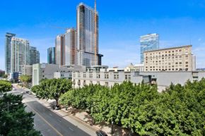 Los Angeles apartment for rent - A cityscape with a mix of modern and older buildings, a tree-lined street, and a clear blue sky.