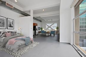 Los Angeles apartment for rent - A modern bedroom with a large bed and a dining area in the background.