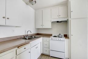 Panorama City apartment for rent - A white kitchen with a sink, stove, and cabinets.