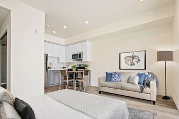 Los Angeles apartment for rent - A modern living room with a grey sofa and a dining table set in the background.