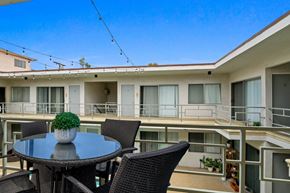 Los Angeles apartment for rent - A balcony with a table and chairs overlooks a building.