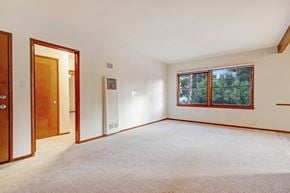 Valley Village apartment for rent - A room with a carpeted floor, a window with a view of trees, and a door.