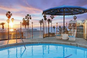 Santa Monica apartment for rent - A pool surrounded by palm trees at sunset.