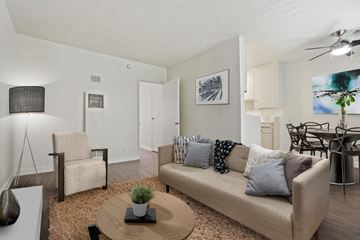 Los Angeles apartment for rent - A living room with a beige couch, a coffee table, and a dining table with chairs.