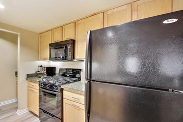 Encino apartment for rent - A black refrigerator in a kitchen with wooden cabinets.
