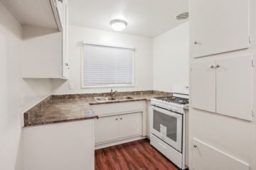 Downey apartment for rent - A kitchen with white cabinets and a granite countertop.
