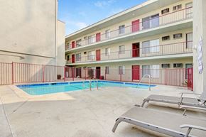 Reseda apartment for rent - A pool area with sun loungers and apartment buildings in the background.