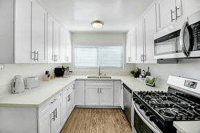 Studio City apartment for rent - a kitchen with white cabinets and a stove and a microwave