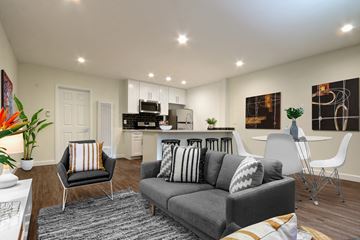 Van Nuys apartment for rent - A modern living room with a grey sofa and a kitchen in the background.