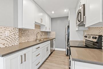 Studio City apartment for rent - A kitchen with white cabinets and a tile backsplash.
