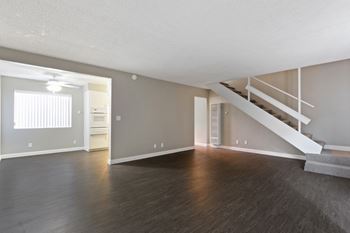 Living room, wood inspired floors throughout the first floor, dining area with ceiling fan on the left