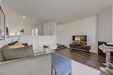 Los Angeles apartment for rent - A grey couch sits in a living room with a television and a fireplace.