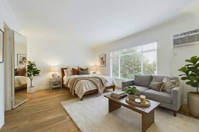 West Hollywood apartment for rent - A well-lit bedroom with a large bed and a grey sofa.