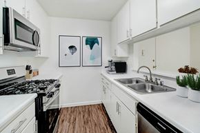 Northridge apartment for rent - a kitchen with white cabinets and a sink and a microwave