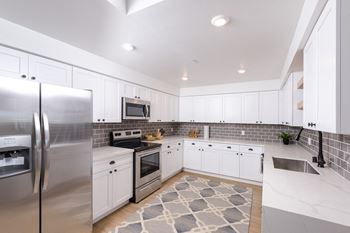 Modern stainless steel appliances include side-by-side refrigerator with ice & water dispenser, range, dishwasher, and microwave