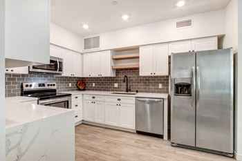 Fully-equipped kitchens with white shaker cabinetry, open shelves, and upgraded oil-rubbed bronze hardware package