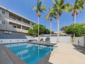 Los Angeles apartment for rent - A swimming pool surrounded by palm trees and apartment buildings.