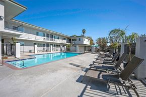 Van Nuys apartment for rent - A pool area with sun loungers and a building in the background.