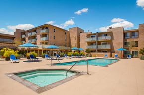 Los Angeles apartment for rent - A swimming pool surrounded by sun loungers and umbrellas in front of a building.