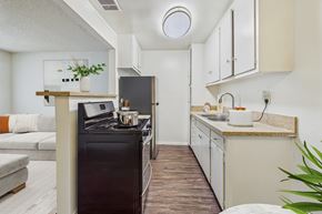 Canoga Park apartment for rent - A modern kitchen with a black stove top oven and white cabinets.