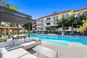 Los Angeles apartment for rent - a pool with lounge chairs and tables and a building in the background