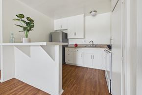 Panorama City apartment for rent - A kitchen with white cabinets and a wooden floor.