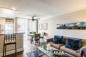 Los Angeles apartment for rent - A living room with a brown couch and a painting of a city skyline on the wall.