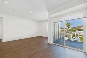 Los Angeles apartment for rent - A room with a sliding glass door leading to a balcony with a view of a building and a palm tree.