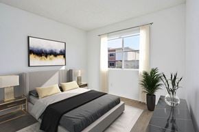 Los Angeles apartment for rent - A bedroom with a large bed, a nightstand with a lamp, a painting on the wall, and a plant on the table.