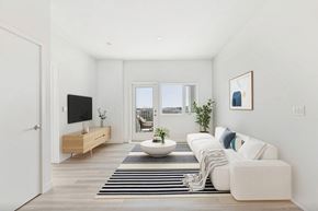 San Pedro apartment for rent - A modern living room with a white sofa, a wooden TV stand, and a large window.