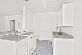 Westminster apartment for rent - a kitchen with white cabinets and a sink and a stove