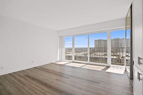 Marina Del Rey apartment for rent - A spacious room with wooden floors and a large window overlooking a cityscape.
