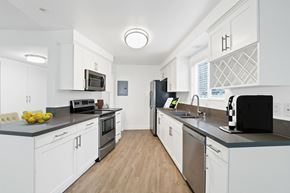 Newport Beach apartment for rent - A modern kitchen with white cabinets and stainless steel appliances.