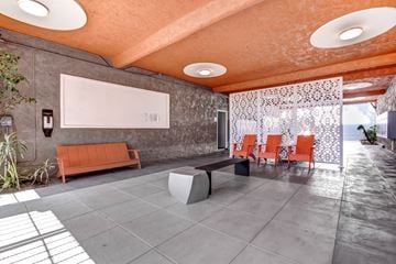 Encino apartment for rent - A modern living room with orange chairs and a grey bench.